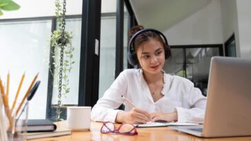 smiling girl in headphones sit at desk look at laptop screen study online happy smart young woman in earphones take web course or training on computer distant education concept free photo